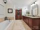 A spacious bathroom featuring a soaking tub, granite counters, and dark wood cabinets at 5624 Warewhip Ln, Charlotte, NC 28210