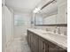 Bathroom with a double sink vanity, large mirror, and tiled floor. Natural light from a window at 5624 Warewhip Ln, Charlotte, NC 28210