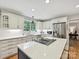 Well-lit kitchen boasts white cabinets, quartz countertops, stainless appliances, and a cooktop island with barstool seating at 5624 Warewhip Ln, Charlotte, NC 28210