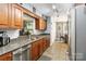 A well-lit kitchen featuring stainless steel appliances, stone countertops, and wood cabinets at 6736 Raeburn Ln, Charlotte, NC 28227