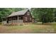 Charming brown home featuring a stone foundation, covered porch, and surrounded by mature trees at 7811 Babe Stillwell Farm Rd, Huntersville, NC 28078