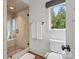 Bathroom featuring a glass shower stall with a tiled floor, white toilet and a window with a wooded view at 7906 Skye Lochs Dr, Waxhaw, NC 28173