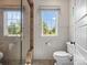 Bathroom featuring a modern toilet, glass shower, white wainscoting, and a window providing natural light at 7906 Skye Lochs Dr, Waxhaw, NC 28173