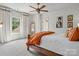 Bright bedroom with large window, wooden bed frame, white bedding with orange accents, and a decorative mirror at 7906 Skye Lochs Dr, Waxhaw, NC 28173