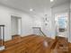 Bright hallway with hardwood floors, white walls, and elegant chandelier; view of bedroom with large world map at 7906 Skye Lochs Dr, Waxhaw, NC 28173