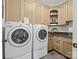 Laundry room featuring modern washer and dryer, wooden cabinets, granite countertops, and a decorative sink at 7906 Skye Lochs Dr, Waxhaw, NC 28173