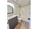 Well-lit bathroom featuring wood-look flooring, gray vanity with light countertop, and white tiled shower-tub at 8809 Reedy Creek Rd, Charlotte, NC 28215
