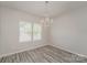 Dining room with gray wood floors and a modern chandelier by a window at 9127 Colwick Hill Ln, Charlotte, NC 28215