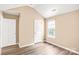 A simple bedroom featuring neutral walls, wood-look flooring, a window, and a white door at 10330 Seedling Ln, Charlotte, NC 28214
