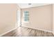 A bright bedroom featuring neutral walls, wood-look flooring, a window, and a white door at 10330 Seedling Ln, Charlotte, NC 28214
