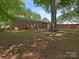 View of the brick home exterior, surrounded by a spacious yard with mature trees and greenery at 1100 Clawson Ct, Charlotte, NC 28209