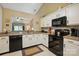 Bright kitchen features white cabinets, black appliances, granite countertops, and a pass-through window to another room at 118 Winborne Dr, Mooresville, NC 28115