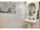 Modern half bathroom featuring a pedestal sink, decorative mirror, and a stylish floral wall art at 14113 Highland Meadow Rd, Charlotte, NC 28273