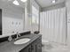 Bright bathroom with white wainscoting, black vanity, and a shower-tub combination at 1413 Devon Dr, Charlotte, NC 28209