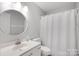 Neutral bathroom featuring a vanity, toilet, round mirror, and a shower behind a curtain at 15324 Yarmouth Rd, Mint Hill, NC 28227