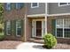 Close-up of a classic brick home's entrance, accented by green shutters and a neatly landscaped garden at 15324 Yarmouth Rd, Mint Hill, NC 28227