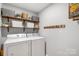 Bright laundry room featuring a washer, dryer, wood shelves, and practical storage solutions at 15324 Yarmouth Rd, Mint Hill, NC 28227