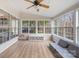 Bright sunroom features large windows, a ceiling fan, and comfortable seating with light hardwood floors at 15324 Yarmouth Rd, Mint Hill, NC 28227