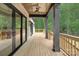 Large covered deck with ceiling fan, wooden floors, and peaceful view of the surrounding woods at 1534 Easy St, Belmont, NC 28012