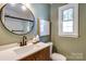 Bathroom with modern sink, dark fixtures, round mirror, and a glass shower at 1904 Lynnwood Dr, Charlotte, NC 28209