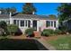 Charming, whitewashed brick home with manicured landscaping, black shutters, and a cozy front porch at 1904 Lynnwood Dr, Charlotte, NC 28209