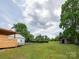 Expansive backyard featuring a pool with fence, small shed, and grassy area surrounded by mature trees at 2054 Hickory Hills Dr, Denver, NC 28037