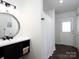 Elegant bathroom featuring dark fixtures, a large round mirror, and a walk-out door at 2054 Hickory Hills Dr, Denver, NC 28037