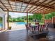 Relaxing covered deck with outdoor dining set, with views of the backyard, pool, and shed at 2054 Hickory Hills Dr, Denver, NC 28037