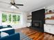 Cozy living room boasts a brick fireplace, floating shelves, and a large window with natural light at 2054 Hickory Hills Dr, Denver, NC 28037