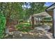 Landscaped backyard with mature trees, brick accents, and a charming pergola covered area at 2126 Norton Rd, Charlotte, NC 28207
