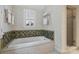 Bathroom showcasing a white soaking tub with decorative tile surround and a window with white shutters at 2126 Norton Rd, Charlotte, NC 28207