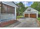 Exterior shot showcasing a two-car garage with wooden doors, an attached structure, and mature trees at 2126 Norton Rd, Charlotte, NC 28207