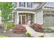 Inviting covered porch with stone details, featuring a red door and a comfortable white rocking chair at 2625 Rea Pond Ct, Charlotte, NC 28226