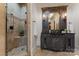 Bathroom featuring a walk-in shower with travertine tiles and a vanity with framed mirror and decorative sconces at 277 Tradition Dr, Mount Gilead, NC 27306