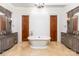 Luxurious bathroom featuring dual vanities, dark countertops, tile floors, and a soaking tub with elegant fixtures at 277 Tradition Dr, Mount Gilead, NC 27306