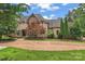 Elegant two-story home featuring a stone and stucco facade, beautiful landscaping, and a winding driveway at 277 Tradition Dr, Mount Gilead, NC 27306