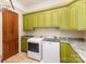 Laundry room with green cabinets, granite countertops, washer and dryer machines, and tile flooring at 277 Tradition Dr, Mount Gilead, NC 27306