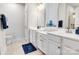 Bright bathroom featuring double vanity sinks, white cabinets and neutral tiled floors and a blue area rug at 5112 Larewood Dr, Charlotte, NC 28215