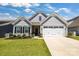 Charming one-story home with a well-manicured lawn, gray siding, a two-car garage and beautiful landscaping at 5112 Larewood Dr, Charlotte, NC 28215