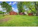 Lush backyard featuring an outbuilding and brick home with green grass and mature trees at 5573 Main St, Fort Lawn, SC 29714