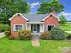 Charming brick home featuring a quaint front porch, light blue shutters, and a well-manicured lawn with lovely landscaping at 5573 Main St, Fort Lawn, SC 29714