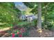 Home exterior with a lush garden featuring vibrant roses and mature trees, creating a picturesque setting at 6005 Bryant Ln, Waxhaw, NC 28173