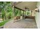 Covered brick patio with outdoor kitchen, porch swing, ceiling fans, and wooded views at 7730 Windsor Forest Pl, Harrisburg, NC 28075