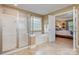Bright bathroom featuring a glass shower, soaking tub, and open access to the Primary bedroom at 7730 Windsor Forest Pl, Harrisburg, NC 28075
