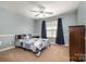Comfortable bedroom with soft carpet, a ceiling fan, and a cozy bed with a patterned blue and white comforter at 7730 Windsor Forest Pl, Harrisburg, NC 28075