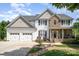 Charming two-story home featuring stone accents, a welcoming porch, and a meticulously maintained front yard at 7730 Windsor Forest Pl, Harrisburg, NC 28075