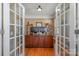 Home office with French doors, hardwood floors, large desk, and built-in shelving for an organized workspace at 7730 Windsor Forest Pl, Harrisburg, NC 28075