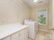 Well-lit laundry room equipped with a washer, dryer, and storage cabinets for convenient household tasks at 7730 Windsor Forest Pl, Harrisburg, NC 28075