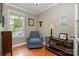 Cozy sitting area with blue armchair, wooden floors, and a window letting in natural light at 7730 Windsor Forest Pl, Harrisburg, NC 28075