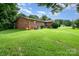 A serene backyard with a well-kept lawn, a brick house, and mature trees, perfect for relaxation at 812 Clinton Ave, Lancaster, SC 29720
